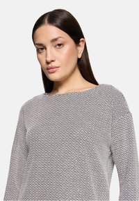 Blomstret bluse i sort og hvid med rund halsudskæring og lange ærmer. Stoffet har en struktureret udseende og en løs pasform.
