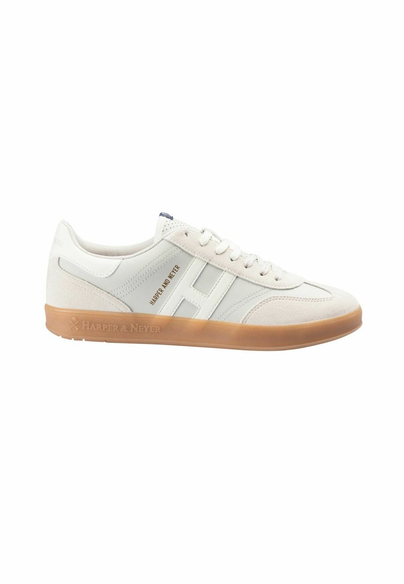 Zapatilla blanca con acentos de ante gris claro, suela de goma texturizada y un diseño minimalista. Presenta una marca en el costado y en la lengüeta.