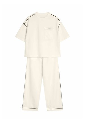 Dwuczęściowy zestaw w off-white z bawełny. Krótki rękaw bluzki z kieszonką na piersi i czarnym wykończeniem, w zestawie z luźnymi spodniami z bocznymi paskami.