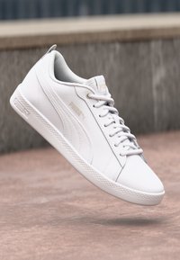 Vita Puma sneakers med en slät syntetisk ovandel, snörning, texturerade sidor och en gummisula med mönstrad slitbana.