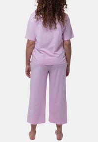 Rosa bomullskläderset med en avslappnad T-shirt med korta ärmar och vida byxor, båda med en mjuk textur.