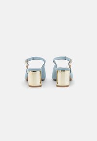 Chaussures slingback en daim bleu clair avec un bout arrondi, dotées d'un talon bloc chunky doré et d'une petite bride avec une boucle dorée.