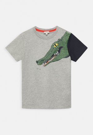 Szary t-shirt z krótkim rękawem z dużą zieloną grafiką głowy krokodyla rozciągającą się od klatki piersiowej do prawego czarnego rękawa.