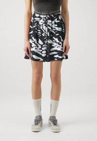 Shorts a rayas en blanco y negro con cintura elástica, hechos de un tejido ligero. Combinados con zapatillas grises y calcetas blancas con canalé.
