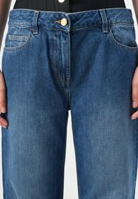 Spijkerbroek in een medium blauwe was, met een klassiek ontwerp, voorzakken, koperen knoop en ton-sur-ton stiksels.