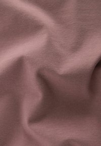 Pehmea, veniv kangas tuhmjas lilas värvitoonis, millel on sile tekstuur pehmete voldide ja kortsudega.