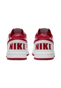 Sneakers bianchi Nike con accenti rossi, dotati di una tomaia in pelle testurizzata, suola in gomma resistente e grande logo "NIKE" sul tallone.