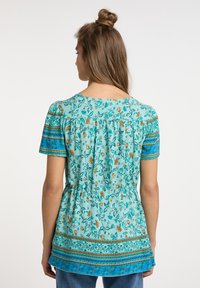 Kurzarmoberteil in Türkis mit floralem Druck, verziert mit Akzentstreifen in Blau und Orange. Leichtes Material mit lässigem Schnitt.