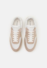 Sneakers with white leather upper, beige suede overlays, and textured rubber sole. Features white laces and embossed logo on tongue.