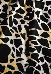 Black and white giraffe print fabric with visible buttons down the center, showing slight folds and texture.