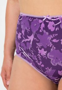 Sous-vêtements taille haute à motif floral violet avec dentelle et petit nœud, portés par une personne vue de la hanche au mi-thigh.