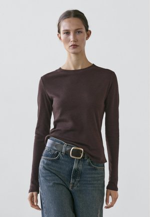 Long-sleeve, dark brown shirt made of soft material, paired with high-waisted, light blue denim jeans and a black belt with silver buckle.