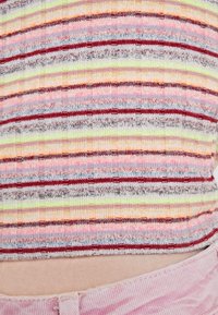 Vícebarevný žebrovaný top se pruhy v růžové, červené a limetkově zelené barvě, s měkkou texturou a přiléhavým střihem, končící nad pasem.