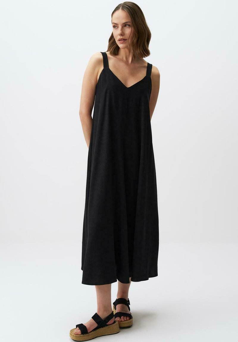 Abito midi nero senza maniche con scollatura a V, caratterizzato da spalline larghe e una vestibilità ampia. Abbinato a sandali espadrilles neri.