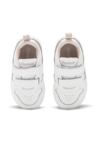 Ett par vita Reebok-toddler sneakers med kardborreband och beige stoppade kragar, sedd ovanifrån på en vit bakgrund.