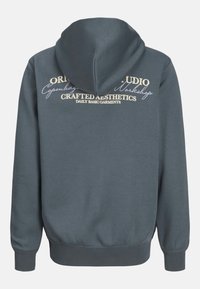 Felpa con cappuccio di colore grigio scuro. Presenta un tessuto texturizzato, con testo stampato in beige chiaro sulla schiena. Polsini e orlo a coste.