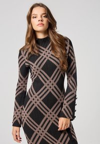 Abito a maniche lunghe a coste in nero e marrone, con un motivo geometrico a forma di diamante, tessuto texture e dettagli con bottoni sui polsini.