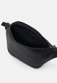 Musta nahkapussi, jossa on teksturoitu pinta ja hopeinen vetoketjusuljenta. Sisäpuoli on vuorattu mustalla kankaalla ja siinä on pieni tasku.