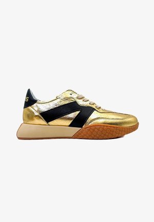 Baskets dorées avec des bandes latérales noires, des lacets beiges et une semelle texturée marron, présentées de profil sur fond blanc.