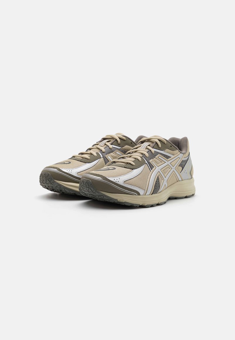 Zapatillas de running con parte superior de malla y sintético en tonos beige y oliva, con una suela texturizada y detalles reflectantes.