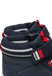 Scarpe ankle boots blu con colletto in maglia a coste, caratterizzato da strisce nere, bianche e rosse, accentuate da lacci rossi e un dettaglio con logo.