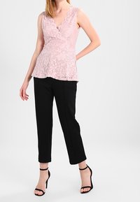 Ljust rosa spetsöverdel med v-ringning och utan ärmar, matchad med svarta cropped byxor och svarta klackar med ankle strap.