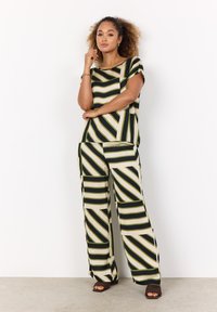 Zwei-teiliges Outfit mit einem kurzärmeligen Oberteil und weiten Hosen. Der Stoff ist mit diagonalen schwarzen, grünen und cremefarbenen Streifen gemustert.