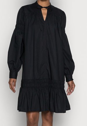 Black dress with long, puffed sleeves, a tie neck, and a gathered, tiered hem. Made from a smooth fabric with a flowing design.