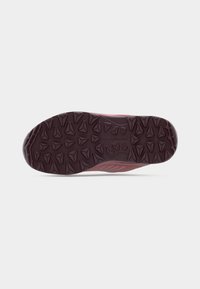 Buitenzool van een trailrunningschoen in donkerbordeauxrood, met een patroon van driehoekige noppen voor grip. Versterkte randen verhogen de duurzaamheid.