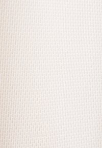 Tessuto texturizzato di un morbido bianco con un motivo intrecciato. Presenta un design a griglia che aggiunge profondità e sottile interesse visivo.