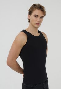 Top nero senza maniche realizzato in tessuto a costine, con scollo rotondo e silhouette aderente.