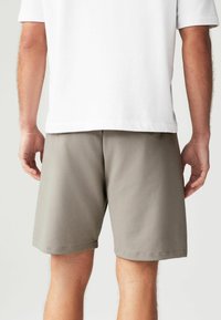 Pantalones cortos grises de tejido ligero, con una cinturilla elástica y un diseño limpio y sencillo. El dobladillo está terminado con costuras mínimas.