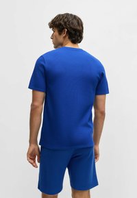 Blue textured t-shirt with short sleeves, round neckline, and matching blue shorts. Fabric appears breathable with a subtle pattern.