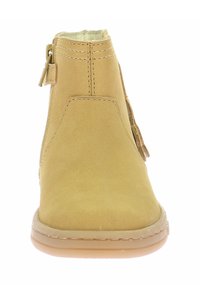 Stivaletto alla caviglia in suede beige con superficie testurizzata, cerniera laterale e suola in gomma flessibile. Presenta dettagli cuciti e una punta arrotondata.