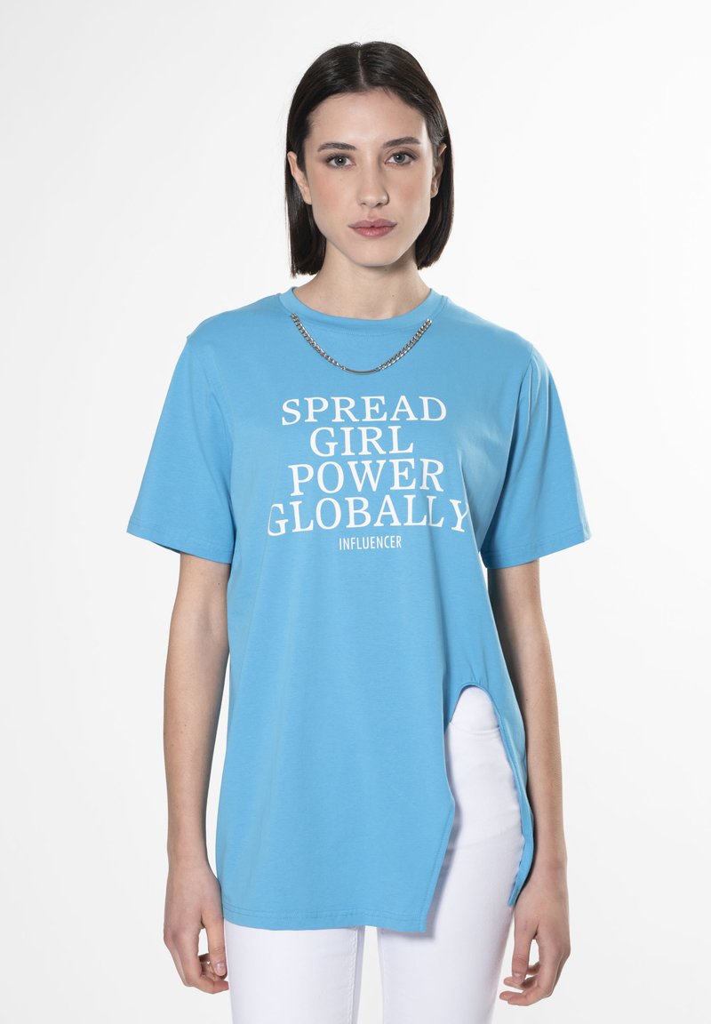 Camiseta de algodón azul con mangas cortas, que presenta un texto blanco que dice "DIFFUNDE EL PODER FEMENINO GLOBALMENTE INFLUENCER" y un detalle de abertura lateral.