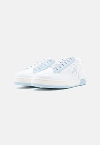 Λευκά αθλητικά παπούτσια με ανοιχτό μπλε λεπτομέρειες, υφασμάτινη υφή, στρογγυλή μύτη και διακοσμητικά κορδόνια· διαθέτουν λογότυπο καρδιάς και ανυψωμένη σόλα.