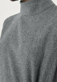 Grauer Rollkragenpullover aus weichem Material. Verfügt über ein tailliertes Design mit hohem Kragen, glatter Textur und minimalen Nähten.
