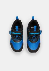 Ett par blåa och svarta barnskor med vita sulor och "Bubblegummers"-logotyp på kardborrebanden, visade ovanifrån.