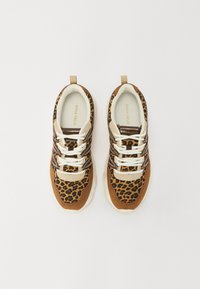 Schwarz-weiß gemusterte Sneakers aus Stoff mit braunen und beigen Akzenten. Verfügt über ein Schnürdesign und helle Sohlen. Logo auf den Innensohlen sichtbar.