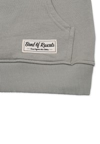Grå sweatshirt med ribbade ärmslut och nederkant. Har en sydd etikett med texten "Band of Rascals" i svart på vit bakgrund.