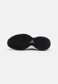 Semelle de chaussure en caoutchouc noir présentant un motif en chevrons, avec une semelle intermédiaire blanche et un petit détail de logo au centre.