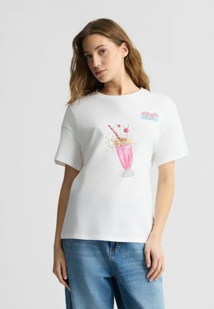 T-shirt en coton blanc avec un graphique de milkshake rose agrémenté de cerises, de pailles et du texte "Diner". Manches courtes et design décontracté.