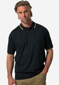 Schwarzes Poloshirt mit Kurzarm und Paisley-Muster, gelbem Kragen und einer Dreiknopf-Leiste. Weicher Stoff mit entspannter Passform.