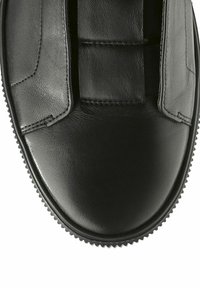 Chaussure noire en cuir à enfiler avec une texture lisse, dotée d'accents cousus et de panneaux élastiques, ainsi que d'une semelle en caoutchouc nervurée.