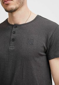 Czarna koszulka henley z krótkim rękawem i trzema guzikami, z delikatnym logo i fakturowanym materiałem dla lepszego wyglądu.