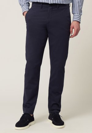 Chinos blu navy con vestibilità slim, realizzati in tessuto misto cotone, dotati di tasche laterali e design frontale piatto, abbinati a scarpe in suede blu navy.