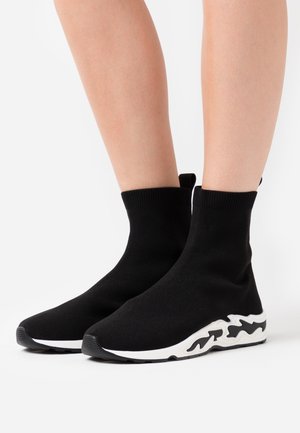 Černé pletené kotníkové boty s texturovaným svrškem, vybavené bílou tvarovanou podrážkou z gumy a kontrastním designem podél podrážky.