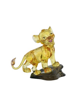 Crystal figurine of a smiling lion, translucent yellow with detailed facets and a brown base resembling rock. Accents include large eyes and ears.