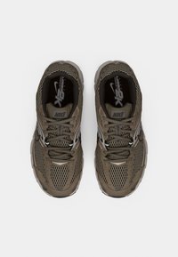 Αθλητικά παπούτσια Nike σε ελιά πράσινο δίχτυ, με στρογγυλεμένη μύτη, κλείσιμο με κορδόνια και μαύρο εσωτερικό με λογότυπο στη γλώσσα.