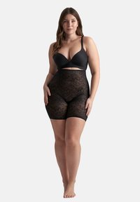 Svart shapewear med blommönster av spets, hög midja och knälång passform. Åtföljd av en svart bh med djup urringning och justerbara band.